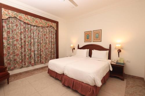 a bedroom with a large bed and a large window at Savoy Suites Noida in Noida