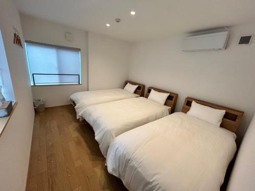 two beds in a small room with a window at 塔の宿 宍道湖 in Matsue
