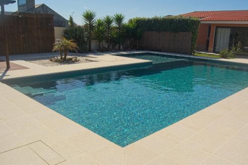 a swimming pool with blue water in a yard at OLA Guesthouse in Esmoriz