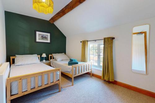 a bedroom with two beds and a green wall at The Winners Enclosure - Country Flat Above a Village Pub in Shrewsbury