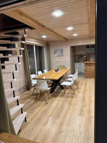 a dining room with a table and white chairs at ForrestVila in Karačiūnai