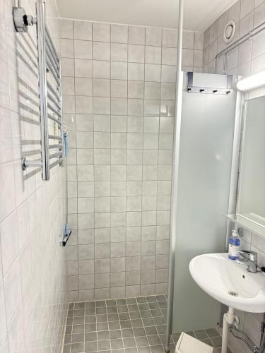 a white tiled bathroom with a sink and a shower at Hotelli Terme 111 in Kilvakkala