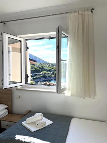 a bedroom with a window with a view of a city at Villa Annabella Beach Apartments - 100m from Sea in Cesarica