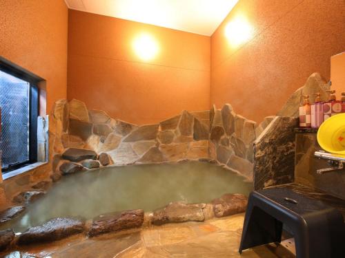 a large hot tub in a room with a stone wall at Gogaku Hotel in Aso