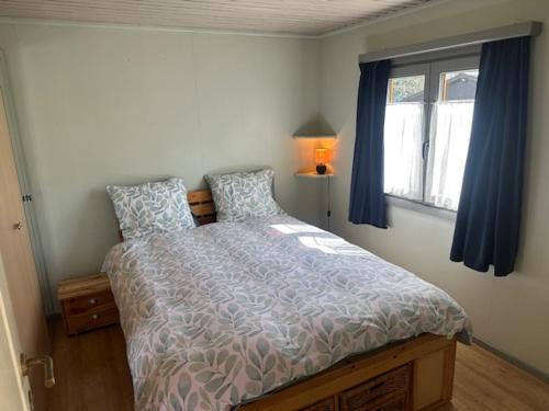 a bedroom with a bed with blue curtains and a window at La tanière du ptit Lou in Resteigne