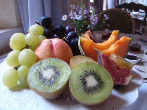 a plate of fruit with kiwis and grapes at Le jardin de Saint Jean in Saint-Jean-aux-Bois