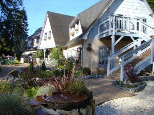 a house with a porch and a deck with plants at Le jardin de Saint Jean in Saint-Jean-aux-Bois