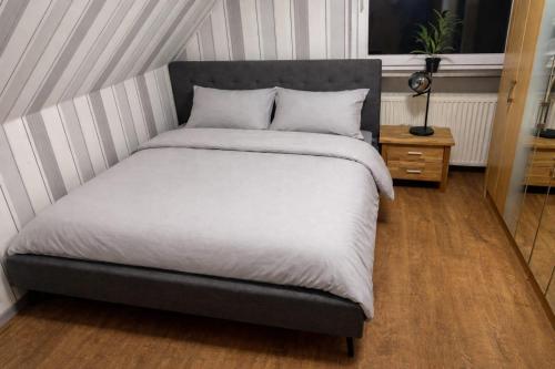 a bed with a gray headboard and white sheets at Hebels Auszeit in Heimbach
