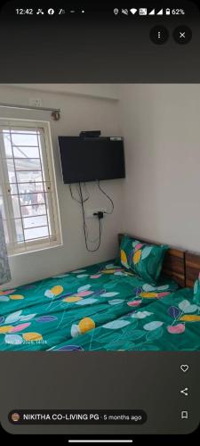 a bedroom with a bed with a television on the wall at nikitha co living pg in Bangalore
