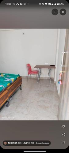 a room with a bed and a table and a red chair at nikitha co living pg in Bangalore