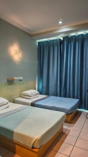 two beds in a room with blue curtains at Highway Inn in Mukah