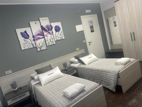 a room with two beds with purple flowers on the wall at B&B Caricone in Orta Nova