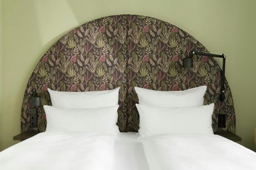 a bed with a headboard and two white pillows at The Cloud One Wien-Staatsoper in Vienna