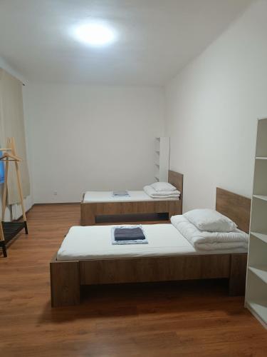 two beds in a room with a white wall at Apartmán Procyon in Prostějov