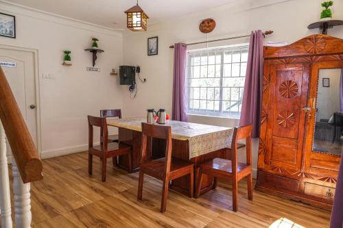 a dining room with a wooden table and chairs at Winterbourne Chalet in Coonoor