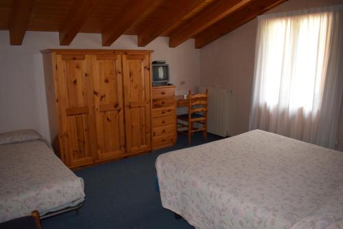 1 dormitorio con 2 camas, armario y TV en Hotel Mignon, en Ponte di Legno
