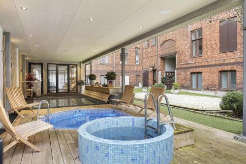 a hot tub on a deck with chairs and a building at Hotel Continental Relax & Spa, BW Signature Collection in Halmstad