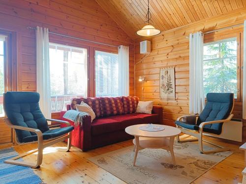 a living room with a red couch and two chairs at Kulkuri in Syöte