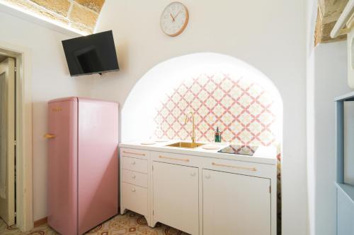 a kitchen with a pink refrigerator and a clock at Pantabrì - Casa Tipica su Mare nel Centro Storico di Gallipoli in Gallipoli