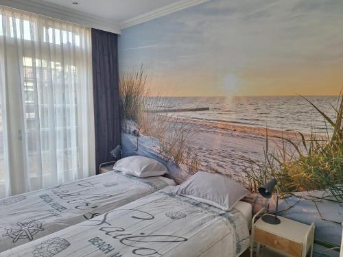 two beds in a room with a beach mural at Appartement Villa Eva Rosa in Wijk aan Zee
