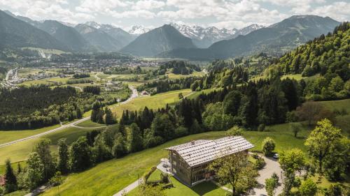 Ein Gebäude auf einem Hügel mit Bergen im Hintergrund in der Unterkunft Der Jägersberg in Fischen im Allgäu
