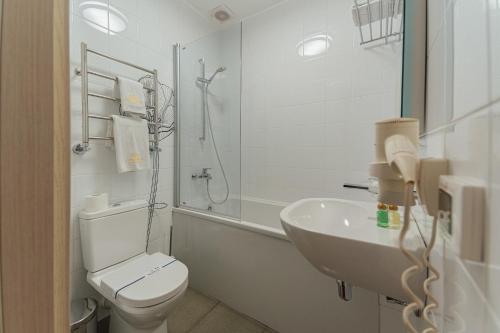 a white bathroom with a toilet and a sink at Boutique Hotel Palais Royal in Odesa