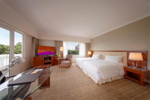 a hotel room with a bed and a flat screen tv at Equatorial Ho Chi Minh City in Ho Chi Minh City