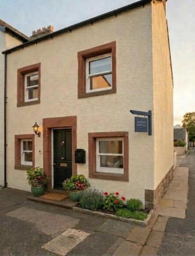 a house with windows and flowers in front of it at Cosy Cottage Stay Book & Unwind in Penrith