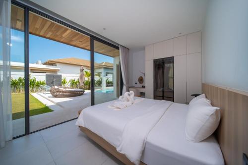 a bedroom with a white bed and a large window at Mouana Breeze Mai Khao VIP 4-bedroom Pool Villa 9911 in Phuket