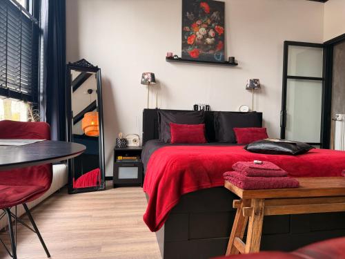a bedroom with a bed with red sheets and a table at B&B Diepzicht in Dokkum