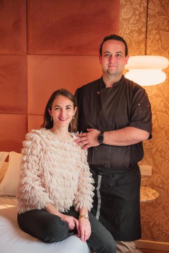 a man standing next to a woman sitting on a bed at Hôtel Restaurant Le Lachens in La Bastide
