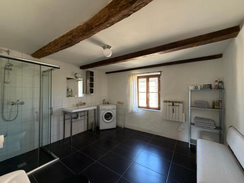a bathroom with a shower sink and a washing machine at L'Epicerie in Melay