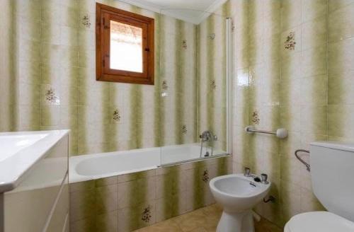 a bathroom with a toilet and a tub and a sink at villa cap marti in El Tosalet