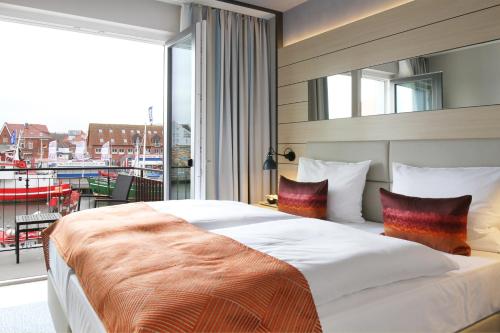 a bedroom with a large bed with a large window at Hafenhotel Meereszeiten in Heiligenhafen