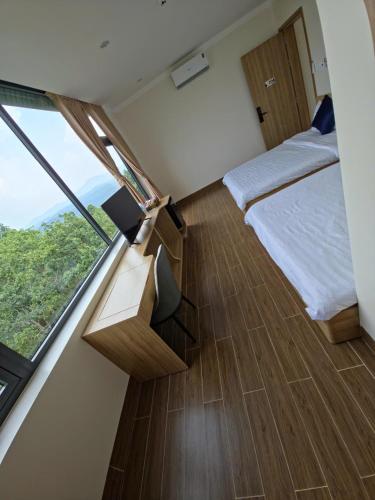 a bedroom with a bed and a large window at Huỳnh Nga Măng Đen Hotel in Kon Plong