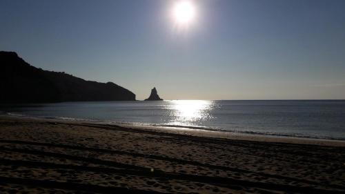 a beach with the sun rising over the ocean at Ava Apartments in Agios Gordios