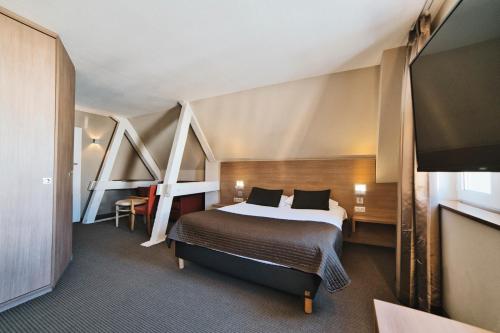 a hotel room with a bed and a flat screen tv at La Clef des Champs - Proche Colmar in Biesheim