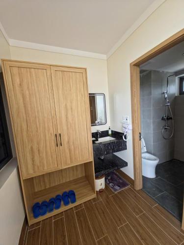a bathroom with a wooden cabinet and a toilet at Huỳnh Nga Măng Đen Hotel in Kon Plong