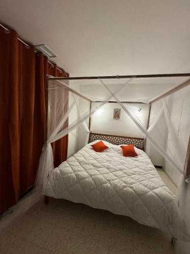 a bedroom with a canopy bed with two orange pillows at Piscine chauffée Clim WIFI 13 personnes Centre Valras-Plage in Valras-Plage