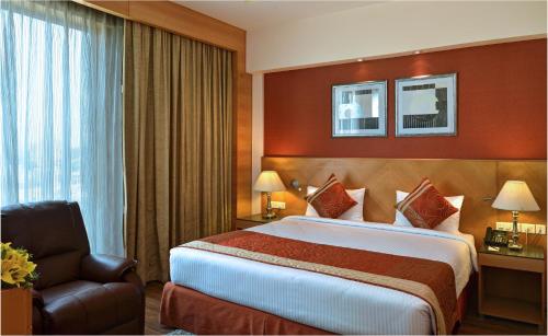 a hotel room with a bed and a chair at Savoy Suites Manesar in Gurgaon
