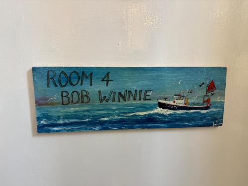 a sign on a wall with a boat in the water at Cadgwith Cove Inn in Cadgwith