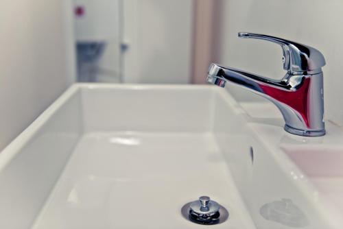 a white sink with a red faucet on it at Appart-Hotel Léopold Liège Centre in Liège