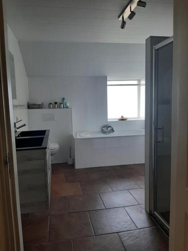 a white kitchen with a sink and a tub at Liroja's Vakantiehuis in Vlagtwedde