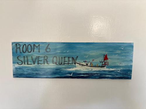 a painting of a boat in the ocean on a wall at Cadgwith Cove Inn in Cadgwith