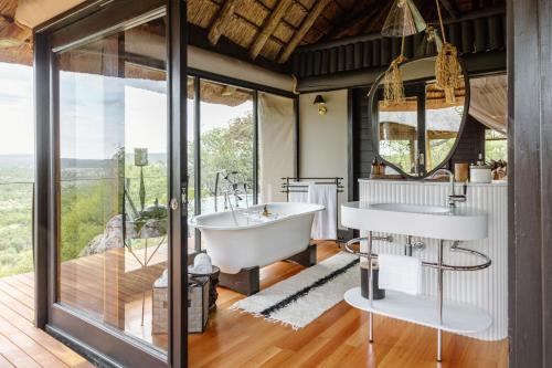 a bathroom with a tub and a large window at Horizon by Ongava in Okaukuejo