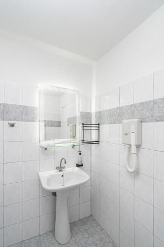 a white bathroom with a sink and a mirror at Flisvos in Sitia