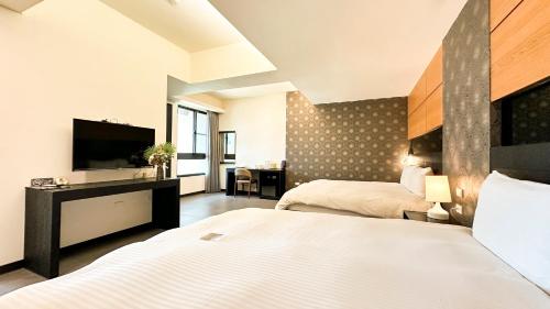 a hotel room with two beds and a flat screen tv at San Juan Easy Stay Inn Tainan in Tainan