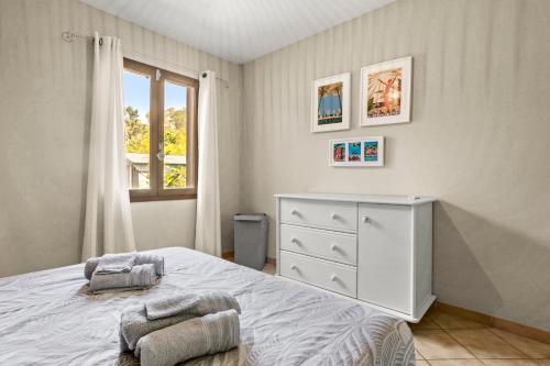 a bedroom with a bed and a dresser and a window at Villa 3 palmiers avec pisicne in Fréjus