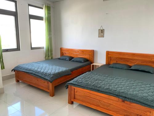 two beds in a bedroom with two windows at Guest house Trung Hiếu in Rạch Giá