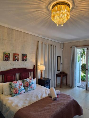 a bedroom with a large bed and a chandelier at Stirling House in Paarl